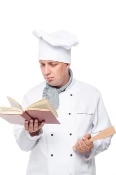 Apprentice chef with a shovel in his hand reading a book on a white backgroun Stock Photos