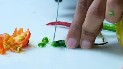 An apprentice chef slicing a green chili on white cutting board with other Stock Footage 244644855