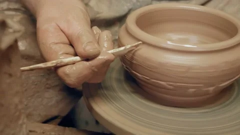 Apprentice decorating clay bowl with plastic knife on kick revolving Video stock 171264995