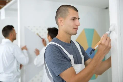Apprentice decorator using a paintbrush Stock Photos