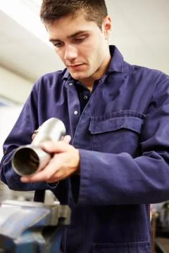 Apprentice engineer checking component on factory floor Foto stock