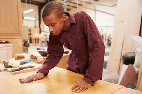 Apprentice Finishing Wood In Carpentry Workshop Stock Photos