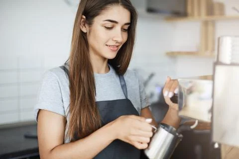 Apprentice lady barista learning how to skim milk in a jug on her first day on a Stock Photos