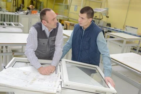 Apprentice learning from senior worker at windows factory Stock Photos