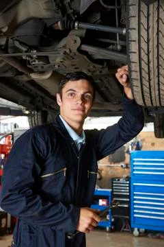 Apprentice Mechanic Working Under Car Stock Photos