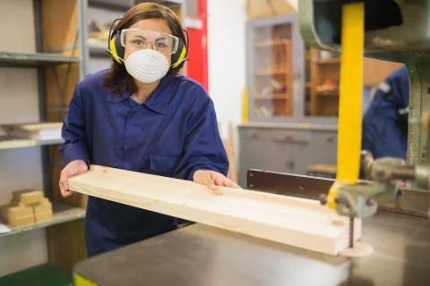 Apprentice wearing safety protection using saw Stock Photos