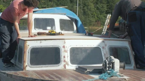 Apprentice working with an experienced carpenter repairs boat roof Stock Footage 286406953