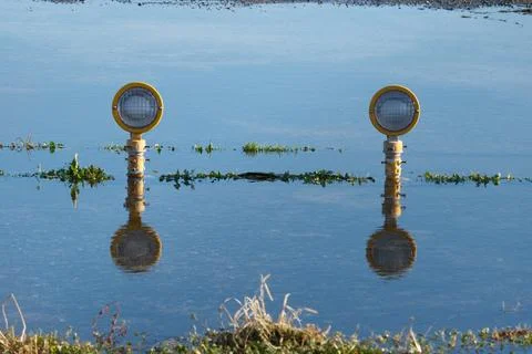 Approach lights reflecting in a puddle after rain on the runway. Stock Photos