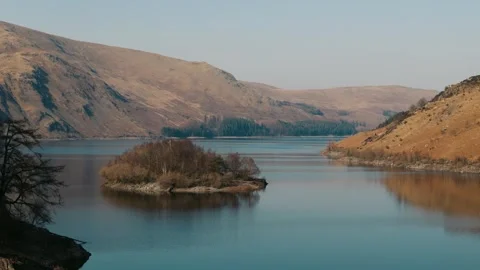 Approaching ascent over Lake District water with multiple islands and sunlit Video stock 313928560