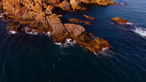 Approaching to the bare rocks lit by the bright sun. Waves splash by the rocky Video stock 321902964