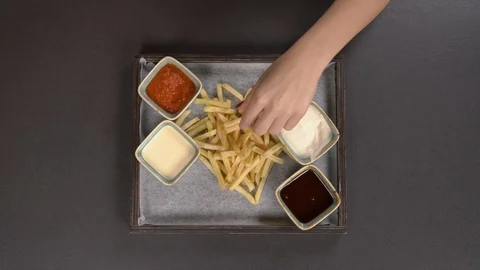 Approaching camera shot of hand taking crispy French fries dipping it into Stock Footage 120678440