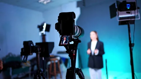 Approaching cameras on tripods and soffits working in photo studio. Woman stands Vídeo Stock 328660800