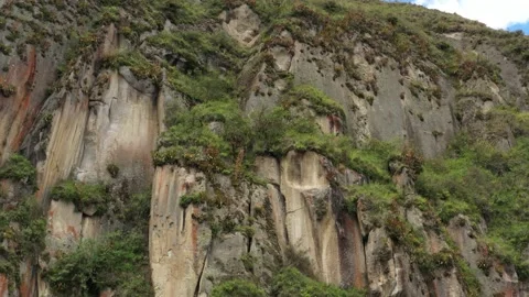 Approaching a cliff with grey brown and red colors that is covered in grass Stock Footage 142755225