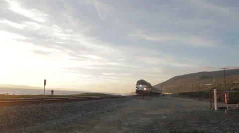 Approaching commuter train along the ocean at sunset 動画素材 47857503