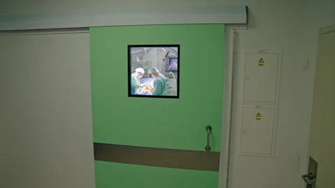 Approaching to the door with square window in modern hospital hall.  Video stock 259439650