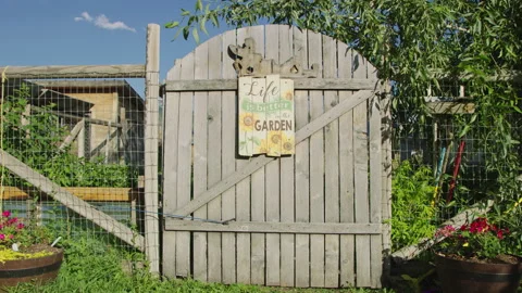 Approaching garden gate with sign reading Life is Better in the Garden Vidéo 248162743