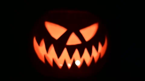 Approaching glowing jack-o-lantern lit from inside Stock Footage 313631299