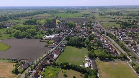 Approaching Lissewege from the Fields – High Drone Push-In by FlyLens Stockbeeldmateriaal 308954874