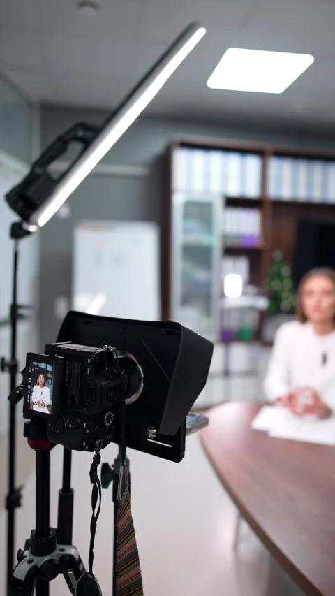 Approaching a modern camera on tripod filming a female speaker. Video stock 300890023