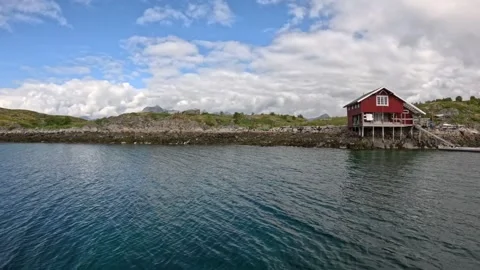 Approaching red traditional rorbu cabin with dock on ocean coast Lofoten Vidéo 344047488