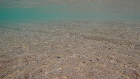 Approaching the shore, sea floor is covered with coarse sand in glare of sun and Stock Footage 322190886