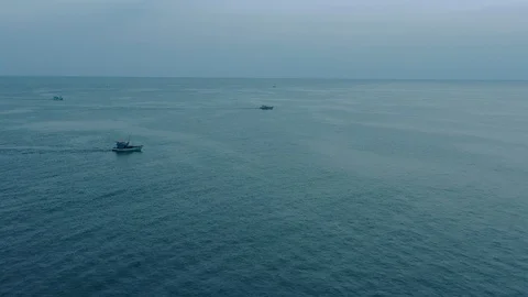 Approaching two floating boats in the ocean passing horizon line early in the mo Stock Footage 124106527