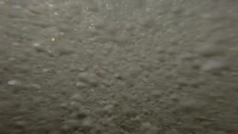 Approaching waves covers camera and throw pebbles at lens, they bounce back and Stock Footage 287733689