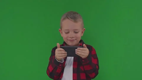 Appy 5 year boy play smartphone video game on isolated green background . Kid Stock Footage 168835855