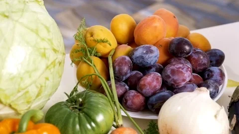 Apricots and plums surrounded by vegetables on table Stock Footage 124961272