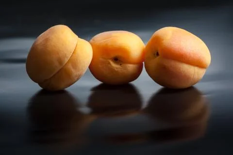 Apricots on black reflective background Stock Photos