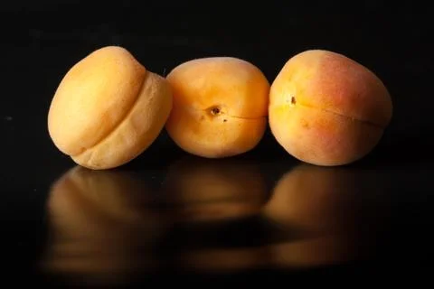 Apricots on black reflective background Stock Photos