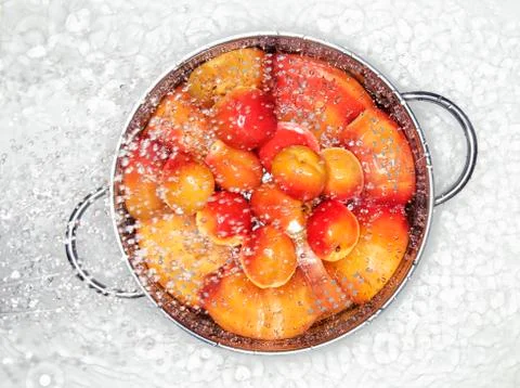 Apricots in a colander being sprayed with water Stock Photos