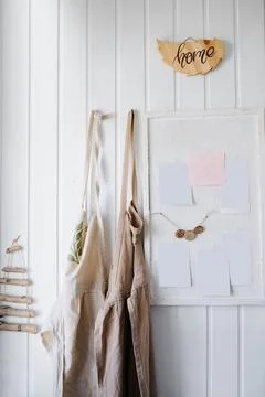 Aprons and a board for notes hang on a white wall Stock Photos