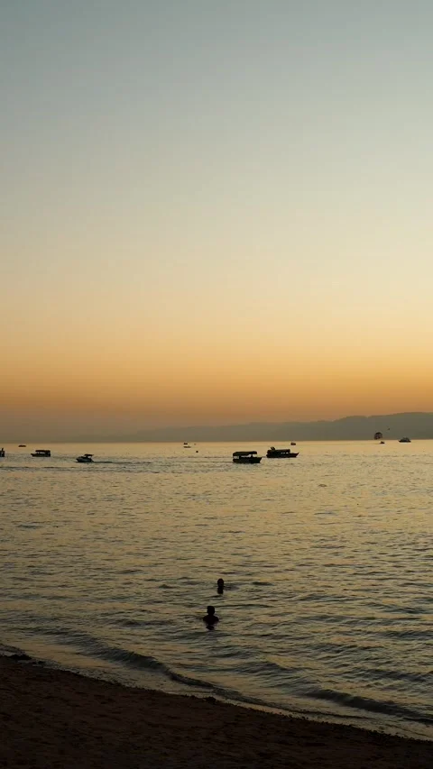 Aqaba beachfront sunset with people swimming and glass boats on the calm Red Stock-Footage 323384257