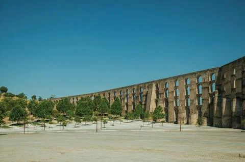 Aqueduct with arches and rectangular pillars in front of wooden square Stock Photos