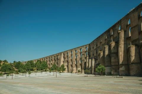 Aqueduct with arches and rectangular pillars in front of wooden square Stock Photos