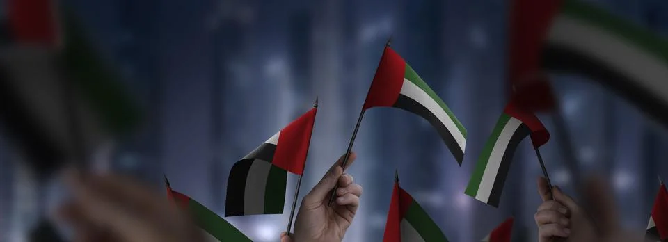 Arab Emirates flags in their hands on a blurred urban background Illustrazione stock