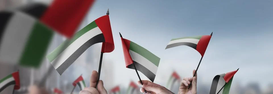 Arab Emirates flags in their hands on a blurred urban background Illustrazione stock