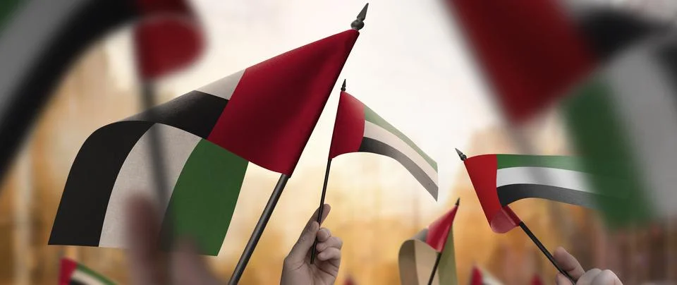 Arab Emirates flags in their hands on a blurred urban background Illustrazione stock