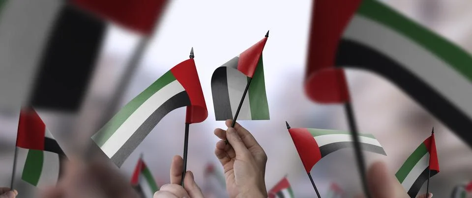 Arab Emirates flags in their hands on a blurred urban background Illustrazione stock