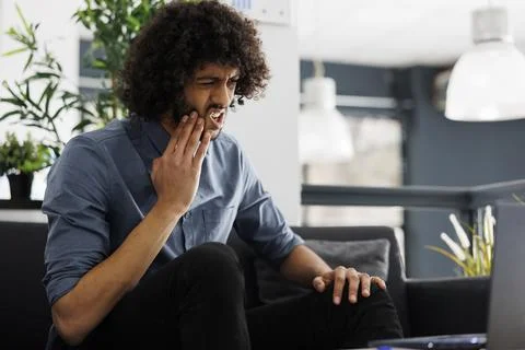 Arab entrepreneur suffering from toothache while working on laptop 库存照片