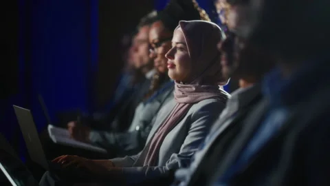 Arab Female Sitting at Crowded Tech Conference with Laptop 스톡 동영상 223043124
