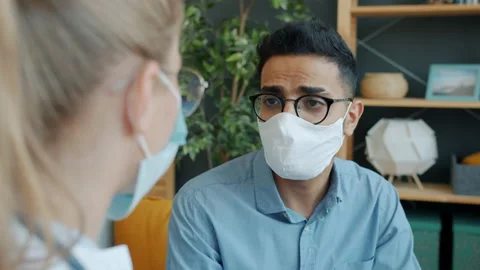 Arab man in face mask talking to doctor at home checking temperature coughing Stock Footage 131249757