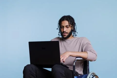 Arab man with physical impairment coding on laptop Stock Photos