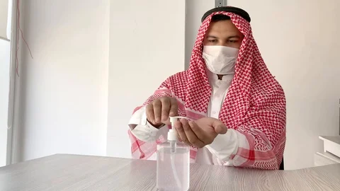 Arab man sanitising hands in a working environment Видео 127642217