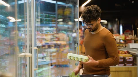 Arab man selecting chicken eggs in grocery store Stock Footage 311485865