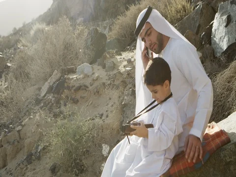 Arab man talking on mobile while his son is looking at binoculars. Stock-Footage 69449494