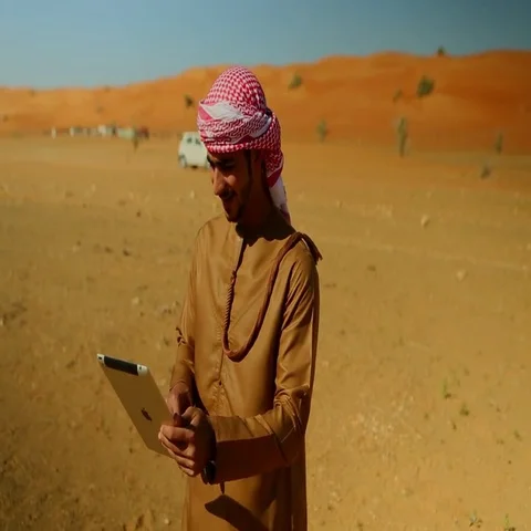 Arab man using digital tablet on desert, car in motion in the background. Stock Footage 69481587