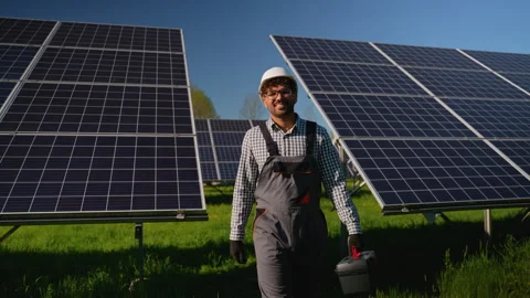 Arabian maintenance engineer walking confidently near solar panels in expansive Stock Footage 314404166