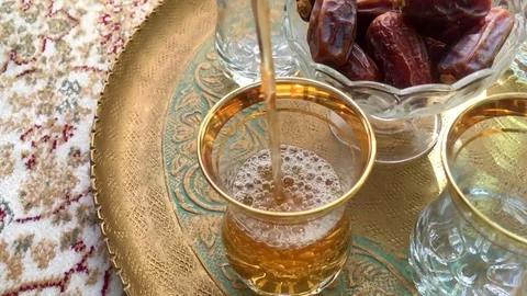 Arabic black tea is being poured in a glass, served along with dates Stock-Footage 74689094